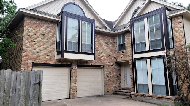 view of front facade with entry steps, a garage, brick siding, and driveway