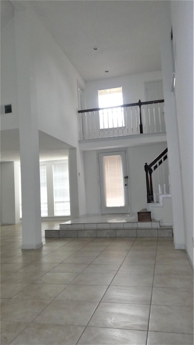 interior space featuring tile patterned flooring, stairs, a high ceiling, and a healthy amount of sunlight