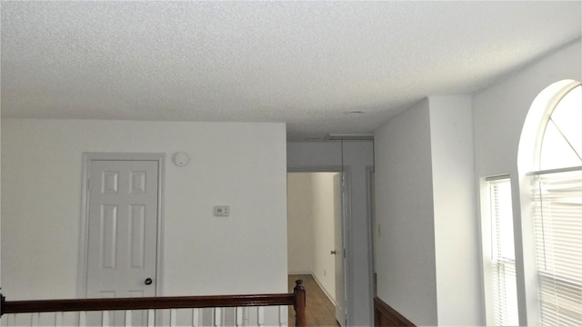 corridor featuring plenty of natural light, a textured ceiling, and wood finished floors