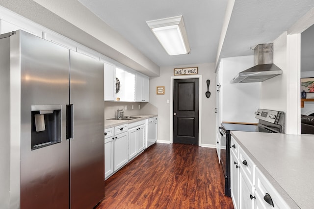 kitchen with a sink, wall chimney exhaust hood, white cabinetry, light countertops, and appliances with stainless steel finishes