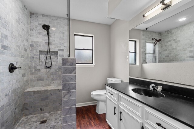 bathroom featuring toilet, visible vents, a tile shower, vanity, and wood finished floors