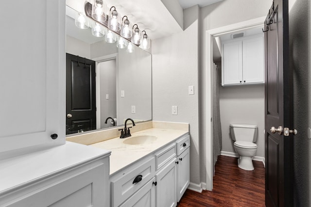 bathroom with toilet, baseboards, vanity, and wood finished floors