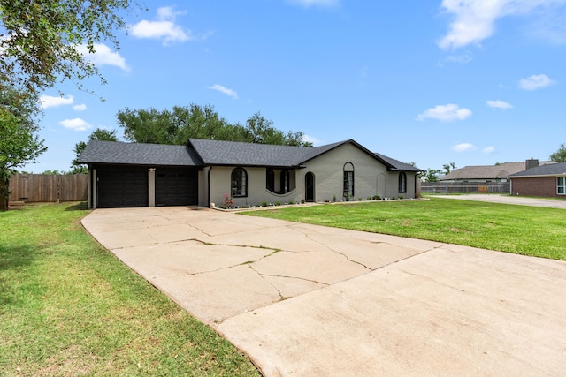 ranch-style home with fence, a garage, concrete driveway, a front yard, and roof with shingles