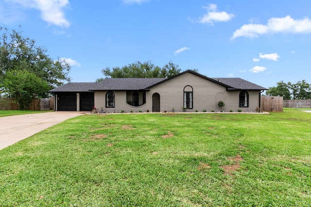 ranch-style home featuring fence, an attached garage, concrete driveway, a front yard, and roof with shingles