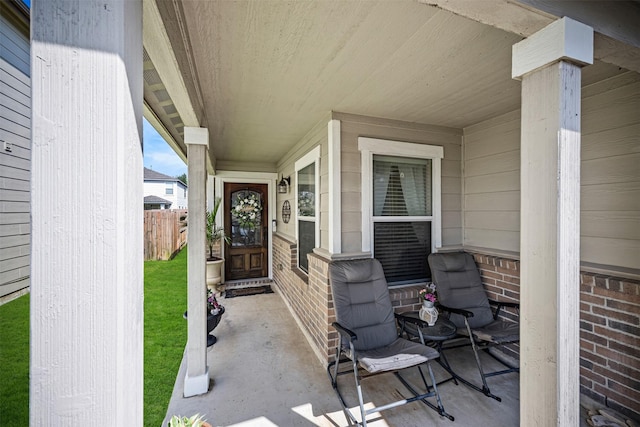 entrance to property featuring covered porch and fence