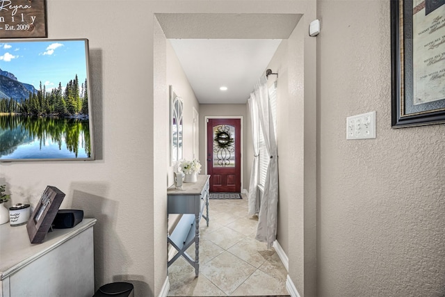 hallway with light tile patterned floors and a textured wall
