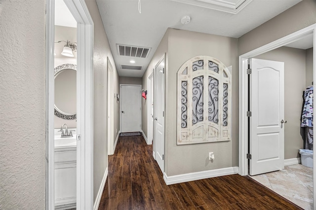 hallway featuring wood finished floors, visible vents, and baseboards