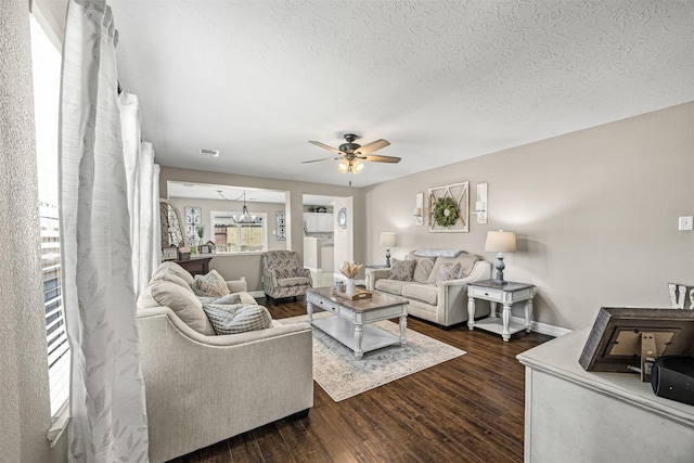 living area with a textured ceiling, visible vents, baseboards, ceiling fan, and dark wood-style floors