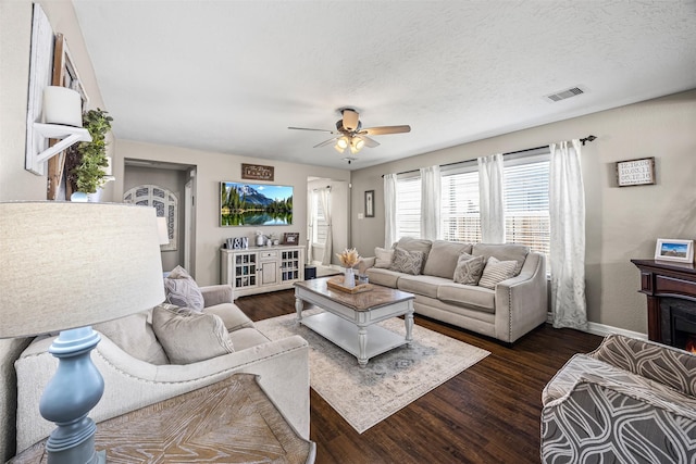 living room featuring baseboards, a ceiling fan, visible vents, and dark wood finished floors