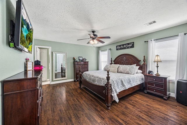 bedroom featuring a textured ceiling, visible vents, dark wood-style flooring, baseboards, and ceiling fan