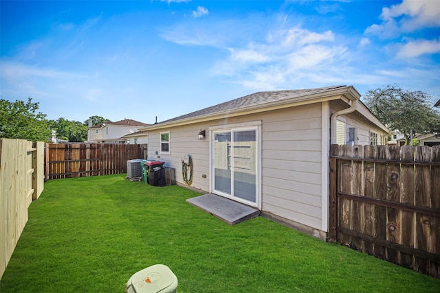 back of house featuring a fenced backyard, cooling unit, and a lawn