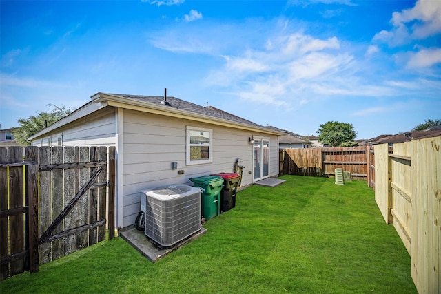 rear view of house featuring a yard, cooling unit, a fenced backyard, and a gate