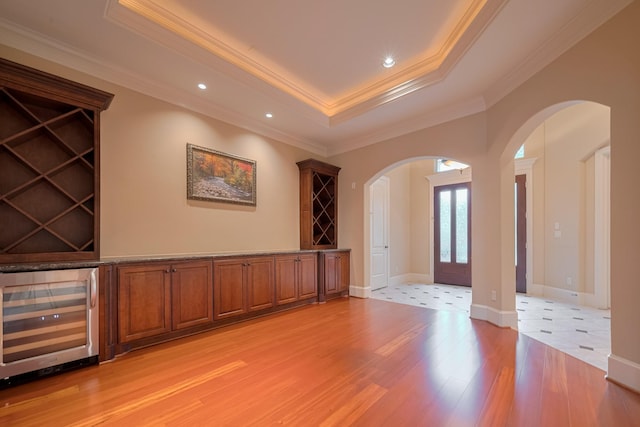 12404 Baymeadow Dr, Pearland, TX 77584 - interior space featuring wine cooler, ornamental molding, arched walkways, a tray ceiling, and light wood-style floors