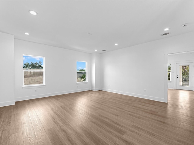 empty room with recessed lighting, baseboards, visible vents, and wood finished floors