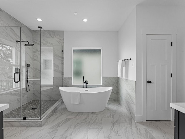 full bathroom with vanity, tile walls, a marble finish shower, and a freestanding tub