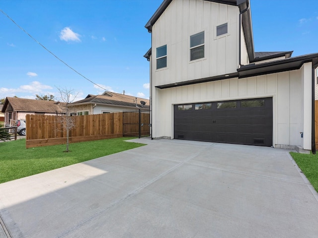 view of side of property featuring fence, a yard, concrete driveway, a garage, and board and batten siding