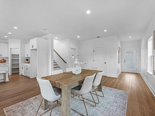 dining area featuring recessed lighting, wood finished floors, baseboards, and stairs