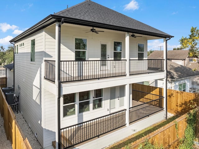 back of house featuring a fenced backyard, ceiling fan, a shingled roof, and a balcony