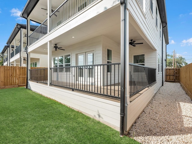 back of property with a fenced backyard, ceiling fan, a lawn, and a balcony