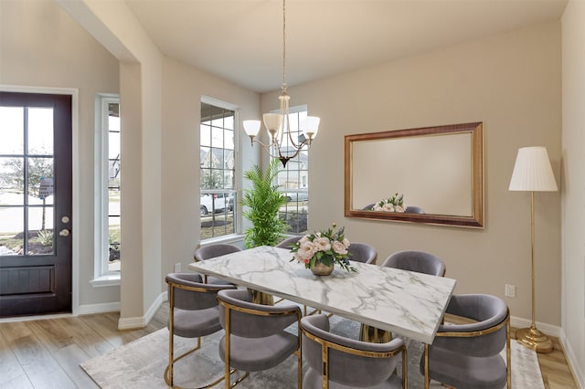 dining room featuring an inviting chandelier, a wealth of natural light, baseboards, and light wood-type flooring