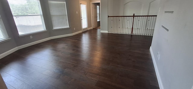 empty room featuring baseboards and dark wood-style floors