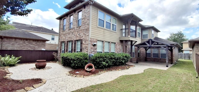 rear view of property featuring a gazebo, a patio area, brick siding, and a balcony