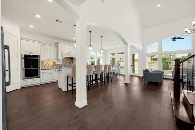 18914 Trinity Star Dr, Cypress, TX 77433 - kitchen featuring stainless steel double oven, a breakfast bar, arched walkways, a ceiling fan, and open floor plan