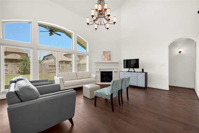 18914 Trinity Star Dr, Cypress, TX 77433 - living room featuring arched walkways, a ceiling fan, a high ceiling, dark wood-type flooring, and a glass covered fireplace