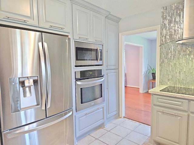 2001 Willow Wisp Dr, Seabrook, TX 77586 - kitchen featuring stainless steel appliances, white cabinets, light tile patterned floors, wall chimney exhaust hood, and light stone countertops