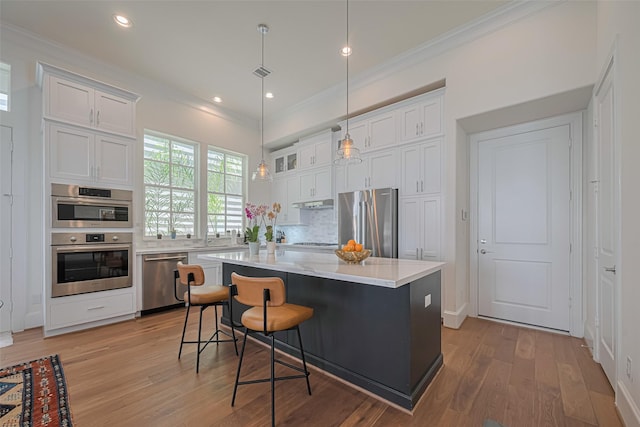 2414 W Kolbe Ln, Houston, TX 77080 - kitchen with stainless steel appliances, ornamental molding, tasteful backsplash, white cabinetry, and light countertops
