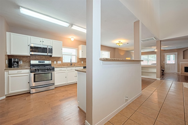 10406 Nickel Grove Dr, Houston, TX 77095 - kitchen with stainless steel appliances, decorative backsplash, white cabinetry, a ceiling fan, and baseboards