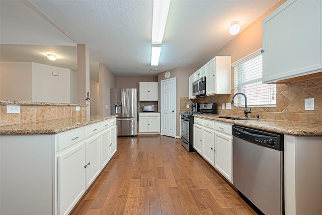 10406 Nickel Grove Dr, Houston, TX 77095 - kitchen featuring stainless steel appliances, a sink, light wood-type flooring, white cabinets, and backsplash