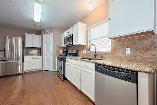 10406 Nickel Grove Dr, Houston, TX 77095 - kitchen with appliances with stainless steel finishes, a sink, white cabinetry, light stone countertops, and dark wood finished floors