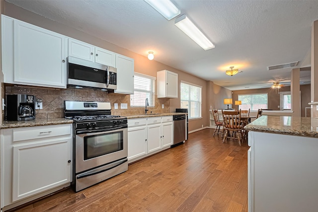 10406 Nickel Grove Dr, Houston, TX 77095 - kitchen with stainless steel appliances, light wood-type flooring, white cabinets, tasteful backsplash, and a textured ceiling