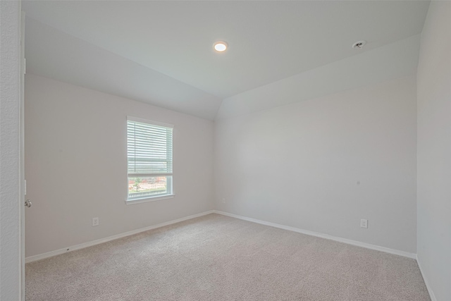 unfurnished room with light colored carpet, baseboards, and lofted ceiling