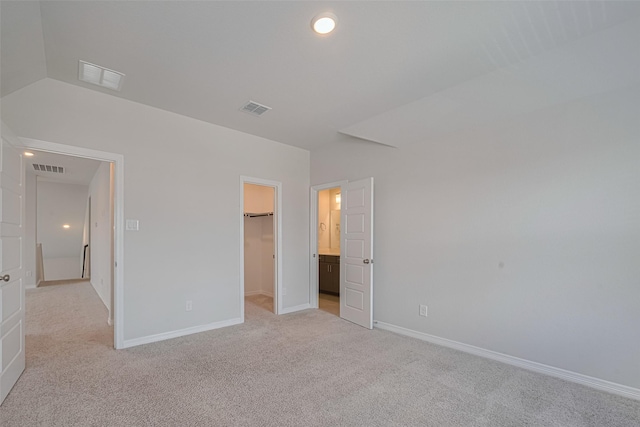 unfurnished bedroom with light colored carpet, a spacious closet, baseboards, and a closet