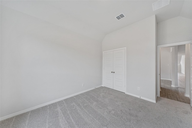 unfurnished bedroom with lofted ceiling, carpet, baseboards, and a closet