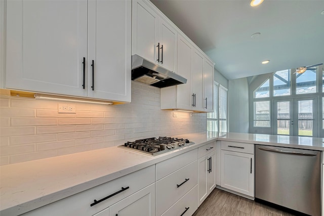 kitchen featuring appliances with stainless steel finishes, under cabinet range hood, white cabinets, backsplash, and recessed lighting