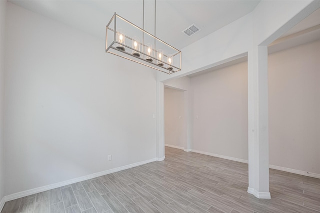below grade area with wood finished floors, baseboards, and a chandelier