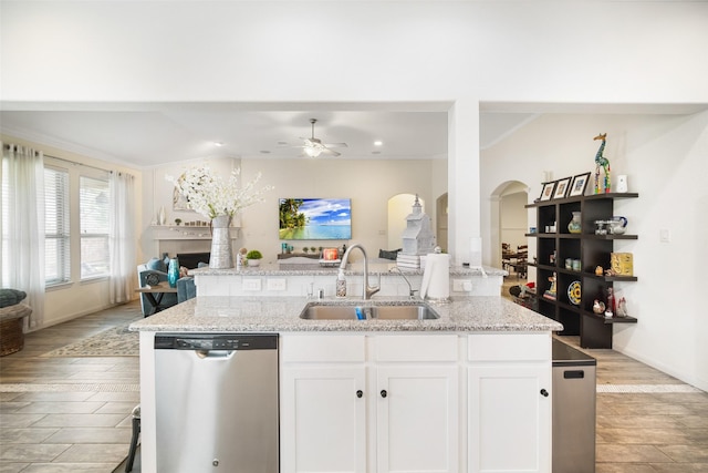 kitchen with dishwasher, a sink, open floor plan, arched walkways, and ceiling fan