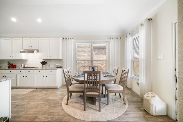 dining area featuring light wood-style floors, crown molding, and recessed lighting
