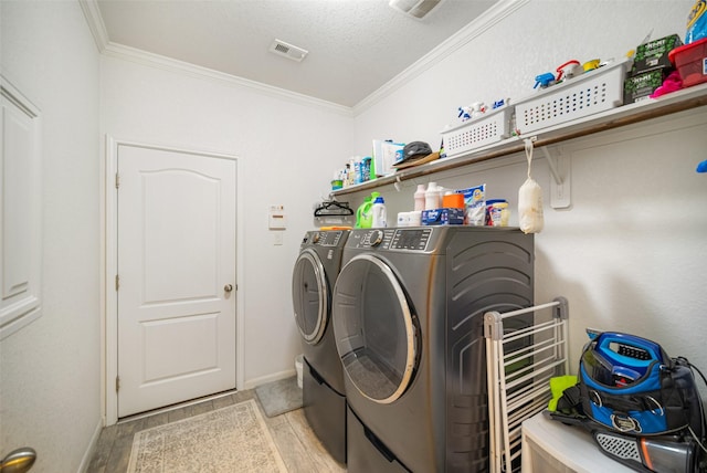 laundry area with washer and dryer, ornamental molding, light wood-type flooring, baseboards, and a textured ceiling