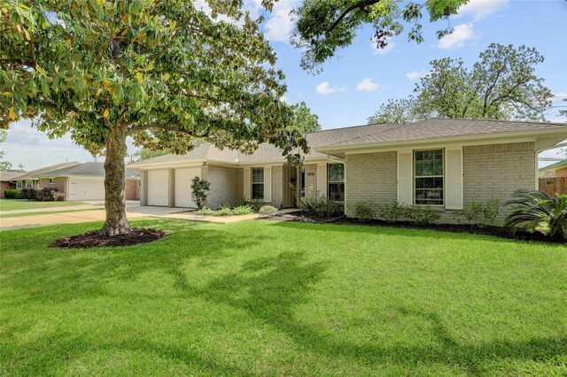 ranch-style home with roof with shingles, an attached garage, brick siding, driveway, and a front yard