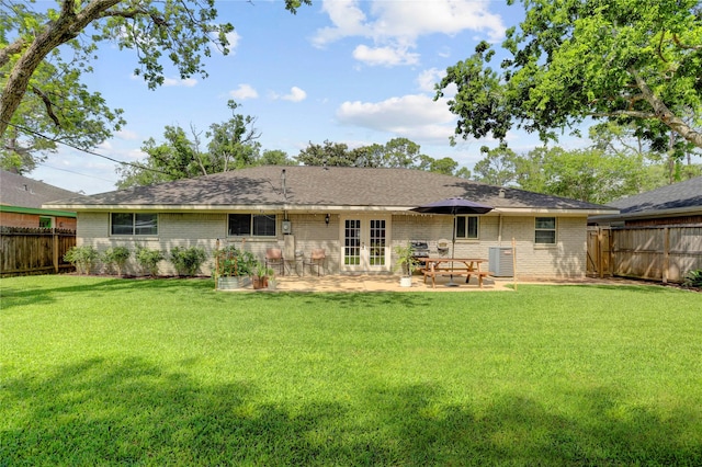 back of property featuring brick siding, french doors, a lawn, and a fenced backyard