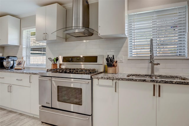kitchen with a sink, wall chimney exhaust hood, double oven range, white cabinets, and tasteful backsplash