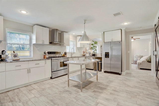 kitchen with stainless steel appliances, decorative backsplash, wall chimney exhaust hood, and visible vents