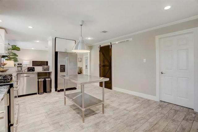 kitchen featuring white cabinetry, a barn door, crown molding, and appliances with stainless steel finishes