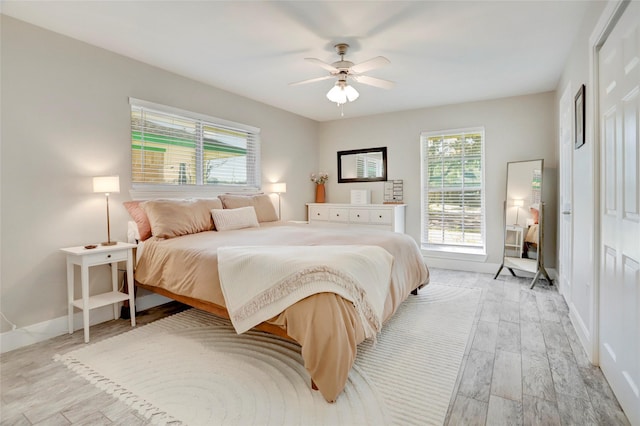 bedroom featuring baseboards, multiple windows, light wood-type flooring, and a ceiling fan