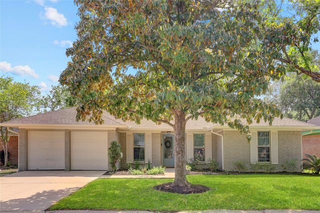view of front of property featuring an attached garage, a front lawn, roof with shingles, brick siding, and driveway