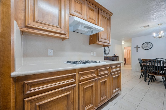 12735 Iroquois St, Houston, TX 77037 - kitchen featuring under cabinet range hood, white gas cooktop, visible vents, a chandelier, and brown cabinets